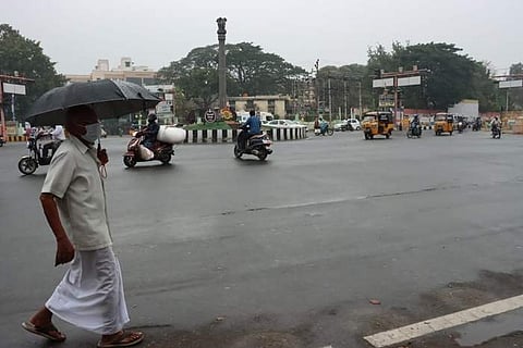 குளிர்ச்சியான சூழ்நிலையை அனுபவித்தவாறு குடை பிடித்தவாறு செல்லும் பெரியவர்.