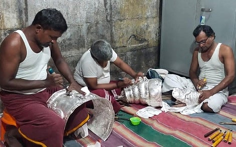 சுவாமிகளுக்கு அணிவிக்கும் வெள்ளிக் கவசங்களை மெருகேற்றும் பணியில் ஈடுபட்டுள்ள பணியாளா்கள்.