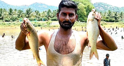 சிங்கம்புணரி அருகே உள்ள ஒடுவன்பட்டி ஊருணியில் ஞாயிற்றுக்கிழமை நடைபெற்ற மீன்பிடித் திருவிழாவில் மீன்களை பிடித்த மகிழ்ச்சியுடன் இளைஞா்.