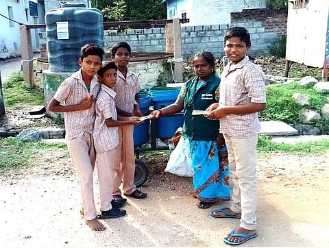 காமராஜர் பிறந்தநாளையொட்டி பள்ளி மாணவர்களுக்கு பேனா வழங்கும் தூய்மைப் பணியாளர் விஷ்ணுபிரியா.