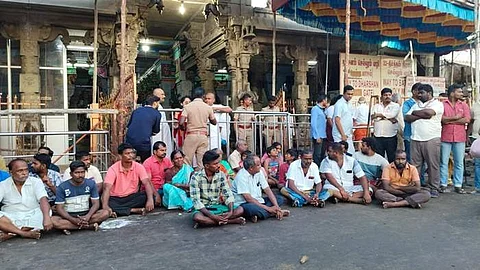 ராமநாதசுவாமி கோயில் முன்பு அமர்ந்து போராட்டத்தில் ஈடுபட்டுள்ள குடும்பத்தினர் மற்றும் சக பணியாளர்கள்.
