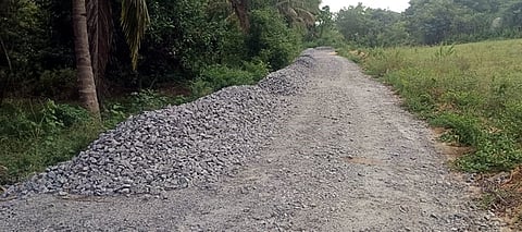 மிட்டாளம் ஊராட்சியில் இருளா் குடியிருப்பு பகுதிக்குச் செல்லும் சாலையில் கொட்டப்பட்டுள்ள ஜல்லிக்கற்கள்.