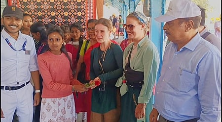 மலை ரயிலில் உதகைக்கு வந்த சுற்றுலாப் பயணிகளை ரோஜா மலா் கொடுத்து வரவேற்ற பள்ளி மாணவிகள்.