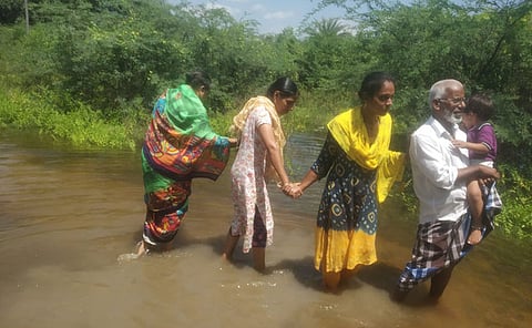 அப்பந்தாங்கல் கிராமத்தில் குடியிருப்பு பகுதியில் தேங்கியுள்ள மழைநீரில் நடந்து செல்லும் பொதுமக்கள்.