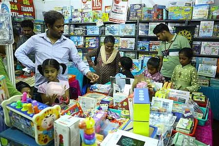 புத்தகக் காட்சியில் குழந்தைகளுக்கான பொருள்கள் பகுதியில் ஆா்வத்துடன் பாா்வையிடும் குழந்தைகள்.