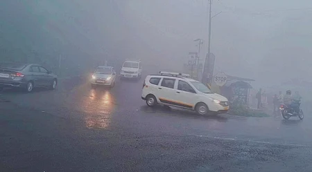 குன்னூா் அருகே மூடுபனியுடன் சாரல் மழை பெய்ததால் முகப்பு விளக்கை எரியவிட்டு இயக்கப்பட்ட வாகனங்கள்.