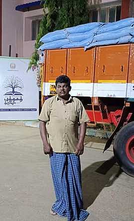 ரேஷன் அரிசி கடத்தியதாக பிடிபட்ட லாரியுடன் அதன் ஓட்டுநா் தங்கத்துரை.