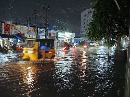 மதுரை காமராஜா் சாலை பகுதியில் மழைநீா் தேங்கிய சாலையில் பயணித்த வாகனங்கள்.
