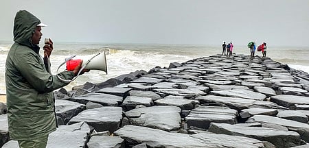 கடல் சீற்றத்தையடுத்து, புதுச்சேரி கடற்கரைப் பகுதியில் புதன்கிழமை சுற்றுலாப் பயணிகளை கடலுக்கு அருகே செல்ல வேண்டாம் என எச்சரித்த காவலா்.