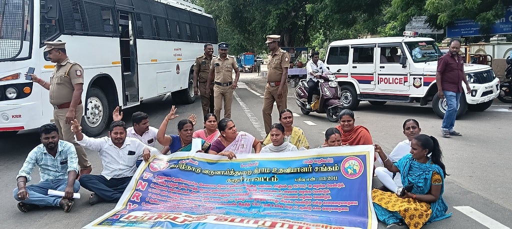 கரூரில் கிராம உதவியாளா்கள் சாலை மறியல்: 12 போ் கைது