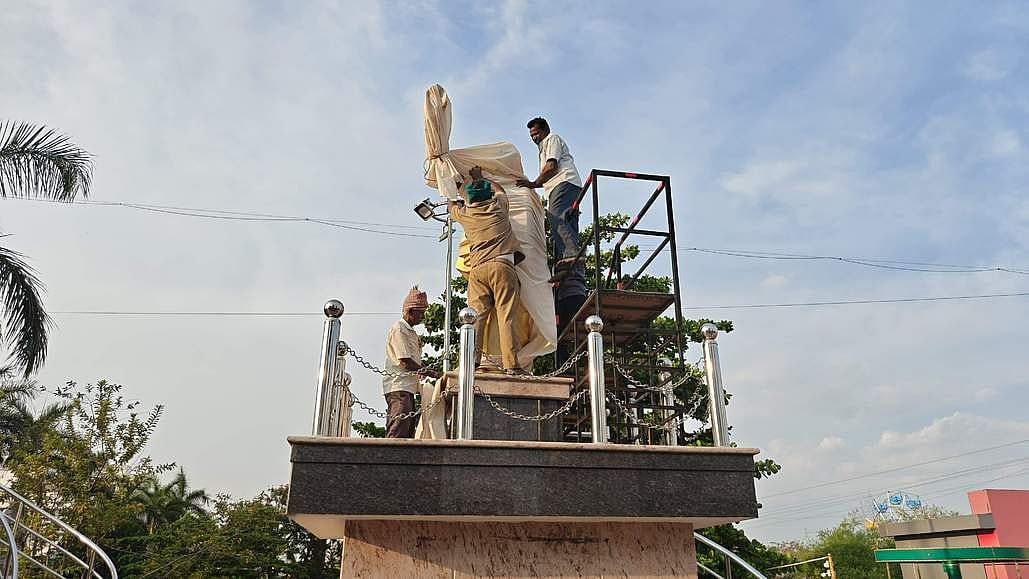 நாமக்கல் - பரமத்தி சாலையில் உள்ள கருணாநிதி சிலையை மூடிய மாநகராட்சிப் பணியாளா்கள்.