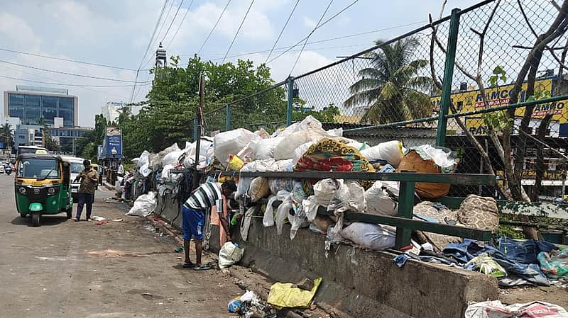 17/06/2026/Karnataka/Bengaluru/ GBA workers have dumped bags of garbage on a footpath adjacent to an open drain forcing people to wal on the road on V