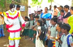 கோமாளி வேடம் அணிந்து மாணவர்களை வரவேற்ற பள்ளி ஆசிரியர்!