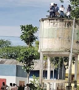பேருந்து வசதி கோரி
குடிநீா் தொட்டி மீது ஏறி பள்ளி மாணவா்கள் போராட்டம்