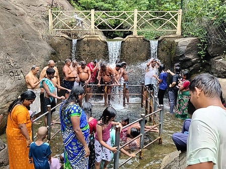 புலியருவியில் குளித்து மகிழும் சுற்றுலாப் பயணிகள்.