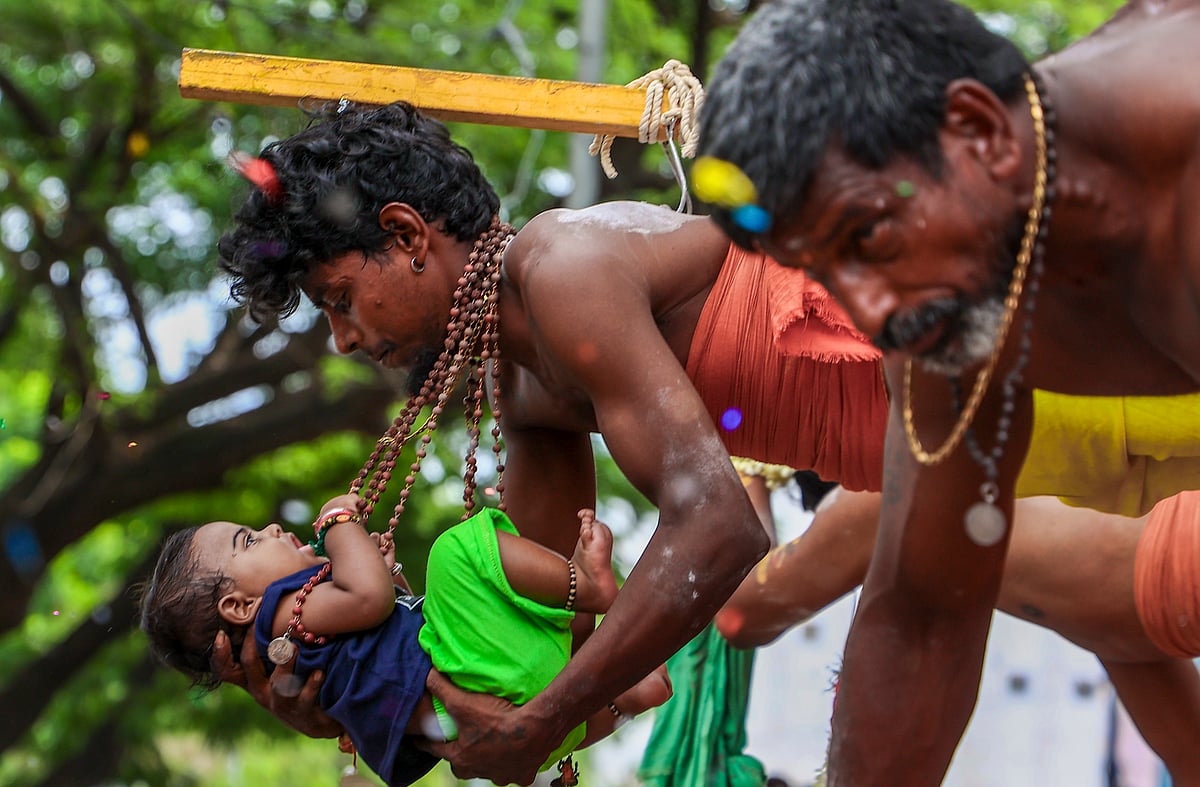 தனது குழந்தையுடன் அலகு குத்தியும், தீச்சட்டி ஏந்தி வரும் பக்தர்.