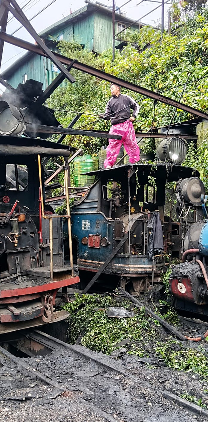 சேதமடைந்த டார்ஜிலிங் ஹிமாலயன் நீராவி என்ஜினை ஆய்வு செய்யும் ரயில்வே ஊழியர்கள்.