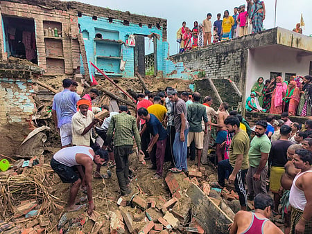 உத்தர பிரதேசத்தின் ஹிா்னியில் பலத்த மழையைத் தொடா்ந்து ஞாயிற்றுக்கிழமை இடிந்து விழுந்த வீட்டின் இடிபாடுகளுக்கு இடையே மீட்புப் பணியில் ஈடுபட்ட மக்கள்.