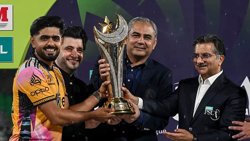 Pakistan’s cricket player and Peshawar Zalmi captain Babar Azam (L) receives the winning trophy from Pakistan Cricket Board (PCB) chairman Mohsin Naqvi (C) after winning the Pakistan Super League (PSL) Twenty20 final match against Hyderabad Kingsmen at the Gaddafi Stadium in Lahore on May 4, 2026. (Photo by Arif ALI / AFP)