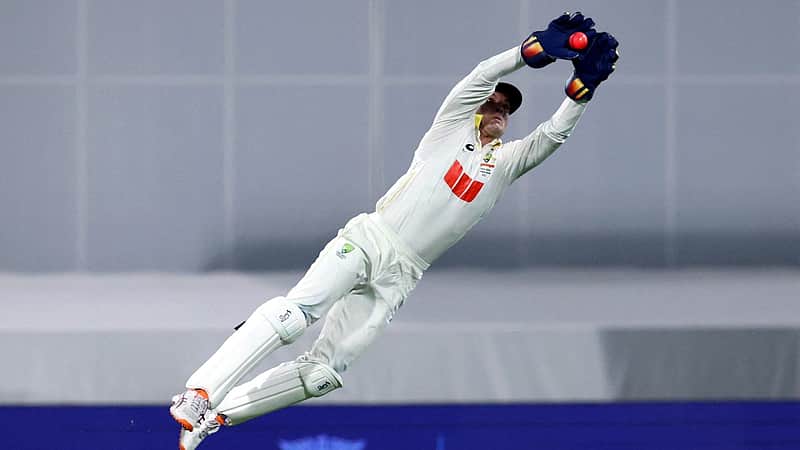 TOPSHOT - Australia’s wicketkeeper Alex Carey dives to catch the ball from a deflection by England’s Will Jacks that is given not out on day three of the second Ashes cricket Test match between Australia and England at The Gabba in Brisbane on December 6, 2025. (Photo by DAVID GRAY / AFP)