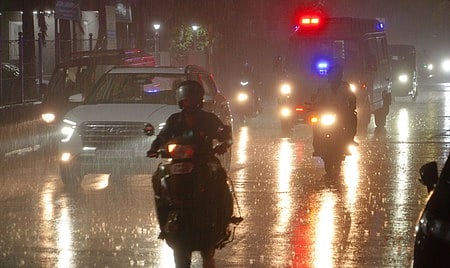 மதுரை கீழவாசல் பகுதியில் வியாழக்கிழமை இரவு மழையினூடே சென்ற வாகனங்கள்.