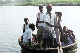 புயலால் சேதமடைந்த தரைப் பாலம்: பரிசலில் ஆற்றைக் கடக்க சிரமப்படும் மக்கள்