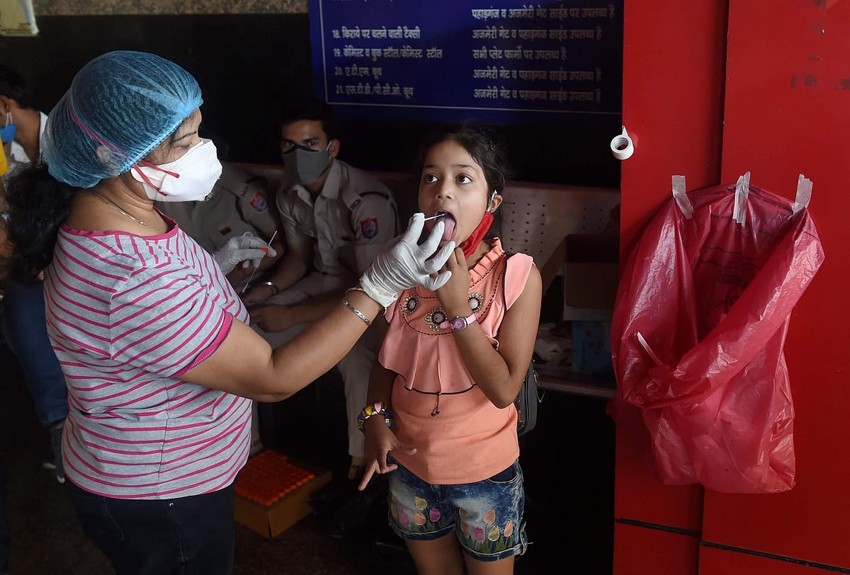 கரோனா தீநுண்மி தொற்று அதிகரித்து வரும் நிலையில், புதுதில்லி ரயில் நிலையத்தில் கரோனா தொற்று நோய் உள்ளதா என்று ஒரு குழந்தையை பரிசோதிக்கும் சுகாதாரப் பணியாளர்.