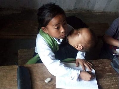 சகோதரியை சுமந்தபடி பள்ளியில் பாடம் பயிலும் மணிப்பூர் சிறுமி: கண்கலங்கவைக்கும் புகைப்படம்