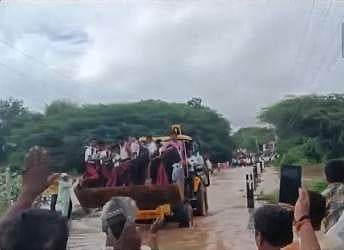 ஜேசிபி மூலம் வெள்ளத்தைக் கடக்கும் பள்ளி மாணவர்கள்