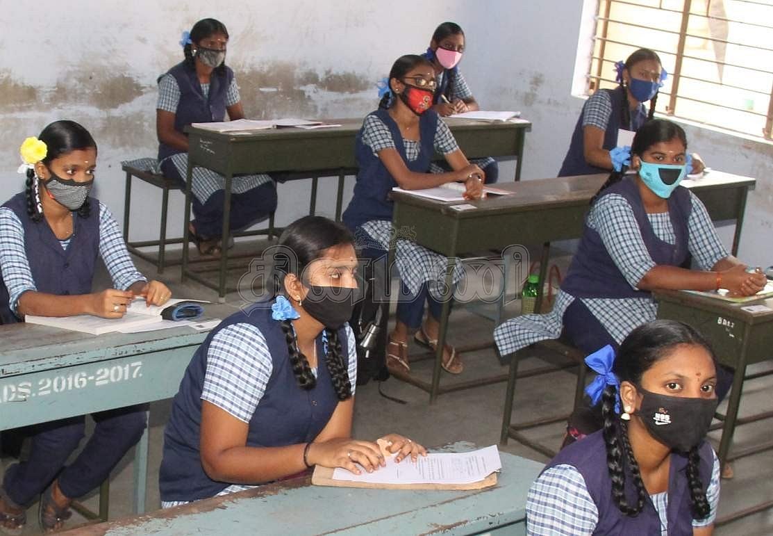 முகக்கவசம் அணிந்தபடி வகுப்பறையில் அமர்ந்திருக்கும் மாணவிகள். 