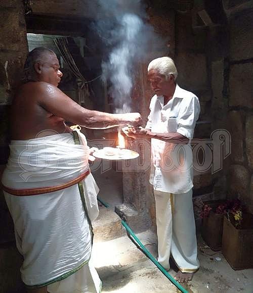 பக்தருக்கு பிரசாதம் வழங்கும் கோயிலின் குருக்கள் மோகன்