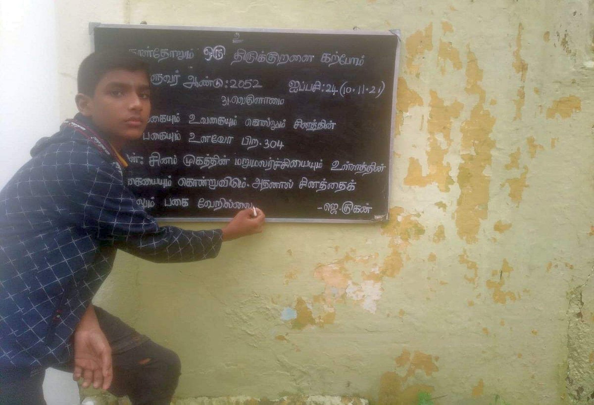 கரும்பலகையில் திருக்குறள் எழுதிப்போடும் குகன்.